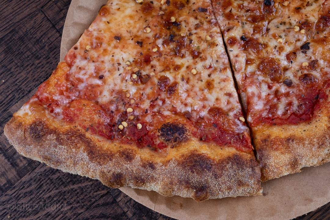 Pizza slice with toppings and basil